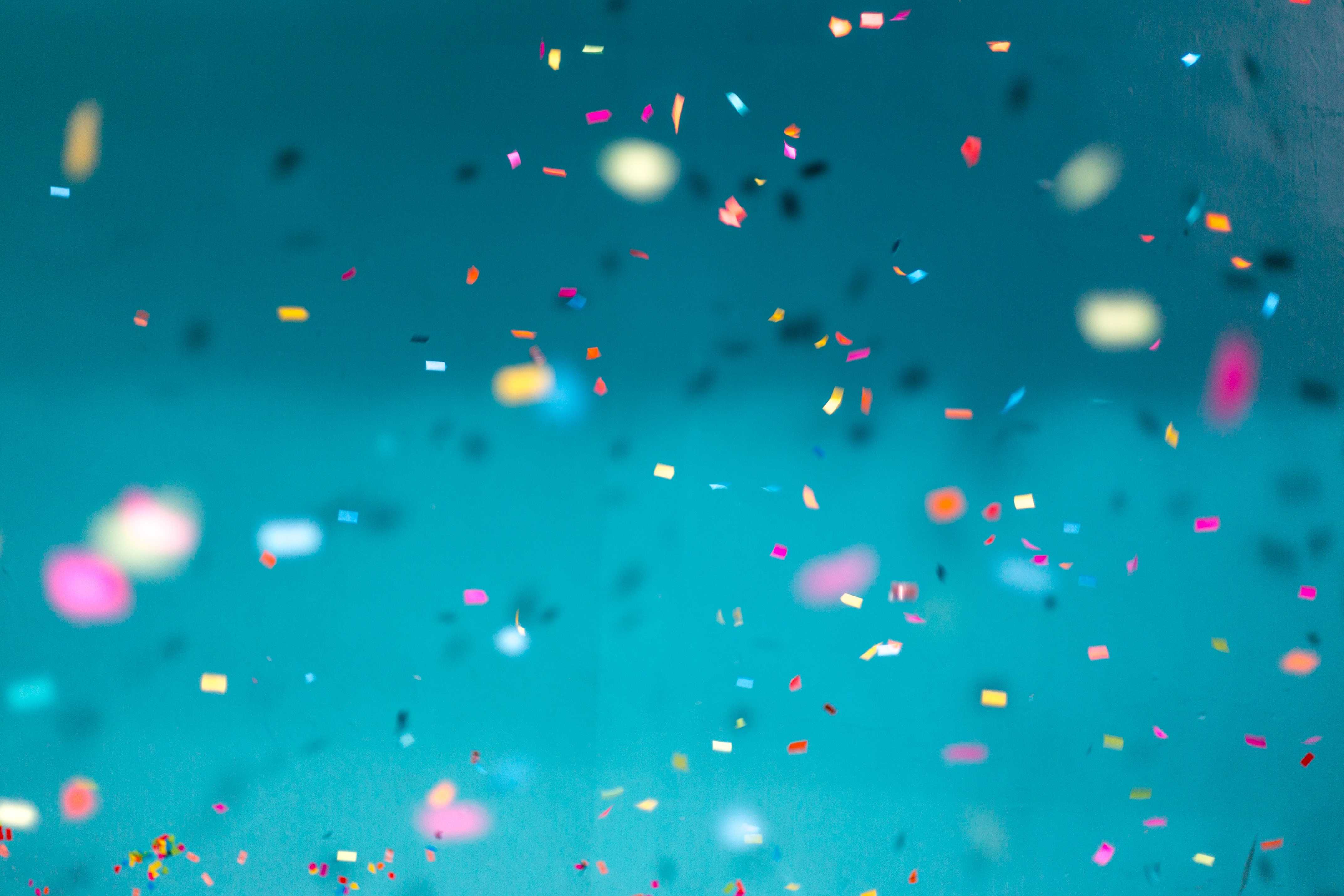 Colorful confetti falling down with a teal background